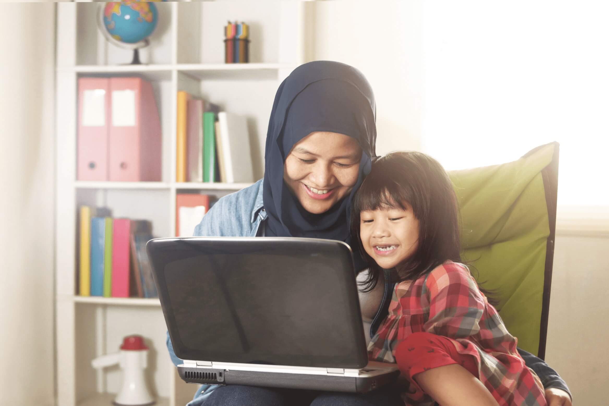 Mother teaching her daughter something from her laptop