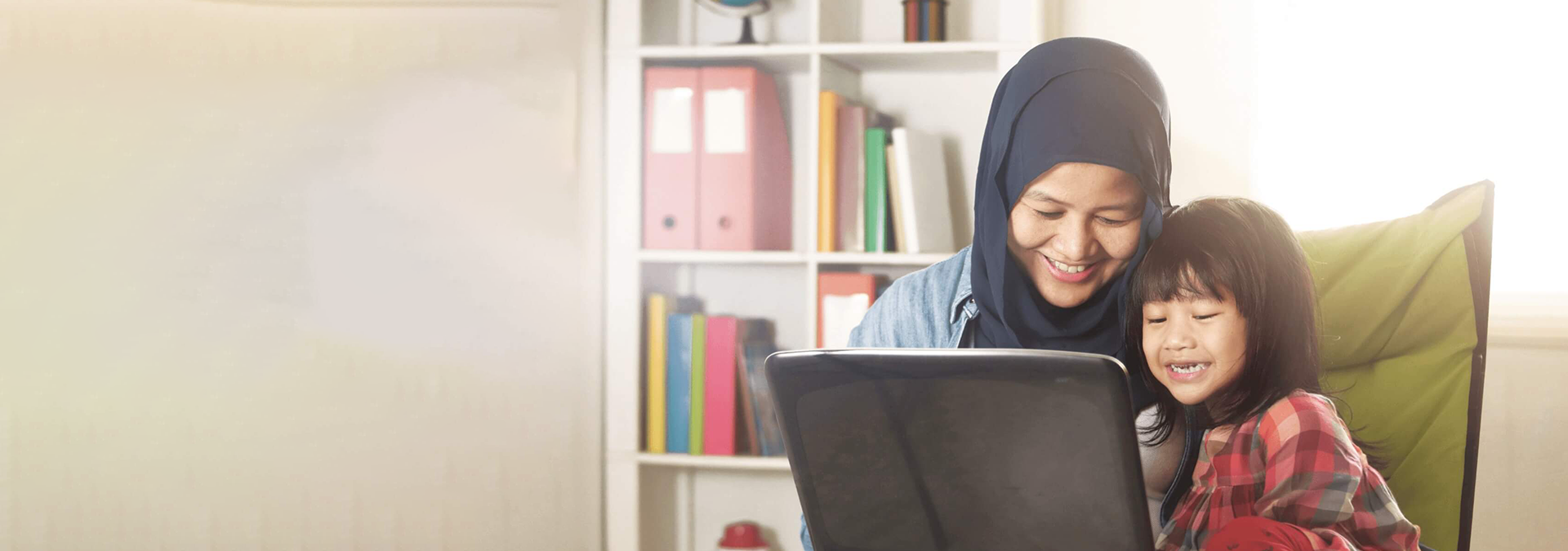 Mother teaching her daughter something from her laptop